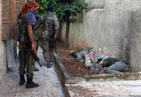 REUTERS- Rebellenkämpfer durchsuchen ein Haus in der Stadt Harem im Norden des Landes nach Anhängern von Baschar al-Assad. Einer bleibt stehen und blickt auf die zusammengekauerten Leichen an der Mauer. Die getöteten Männer sollen Assad-Unterstützer gewesen sein. sie von den Rebellen hingerichtet.